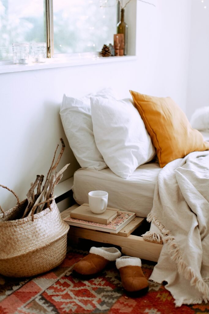 A cozy bedroom setup featuring pillows, a blanket, and warm-toned decor.